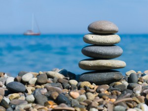 Stack of stones on beach and yacht in sea
